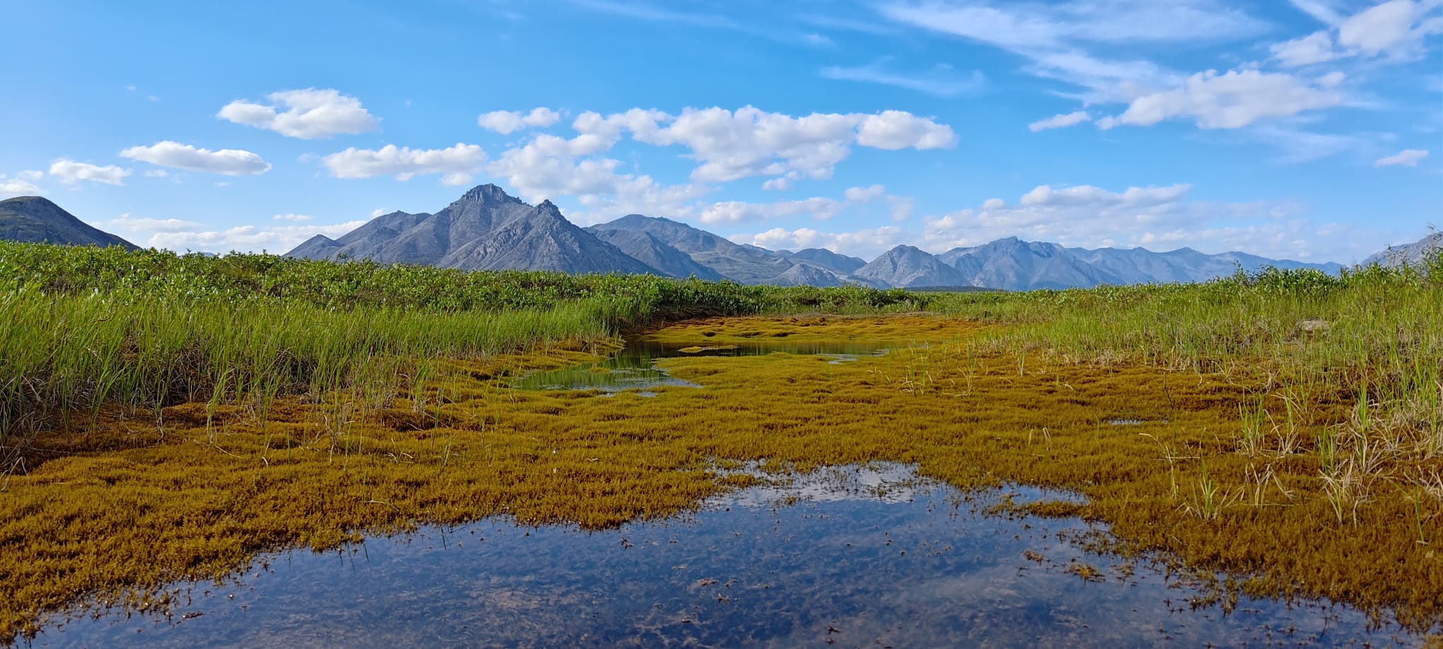 Weite Landschaft mit Bergen, Wasser und offenem Himmel